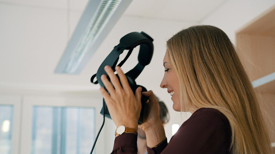 Eine Frau setzt eine VR-Brille auf
